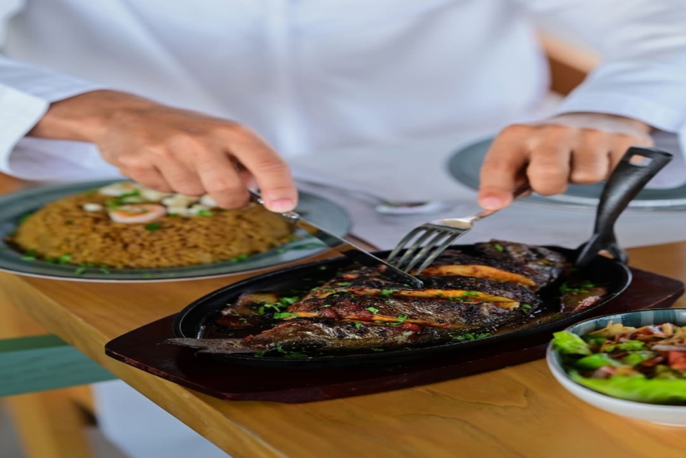 man enjoying fresh sea food with knife and fork
